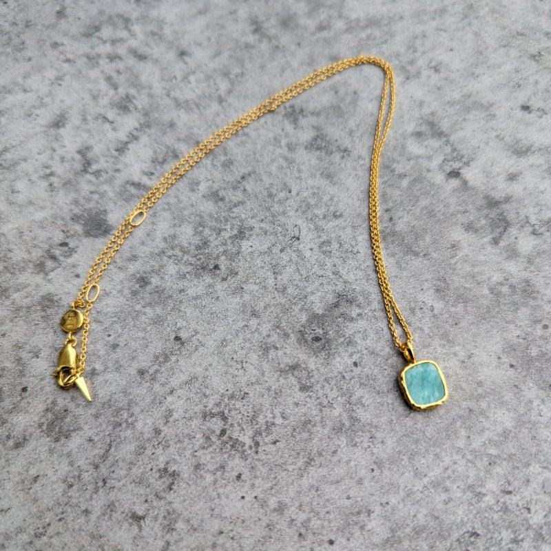 Photo of amazonite blue stone gold plated necklace on a grey marble effect background.