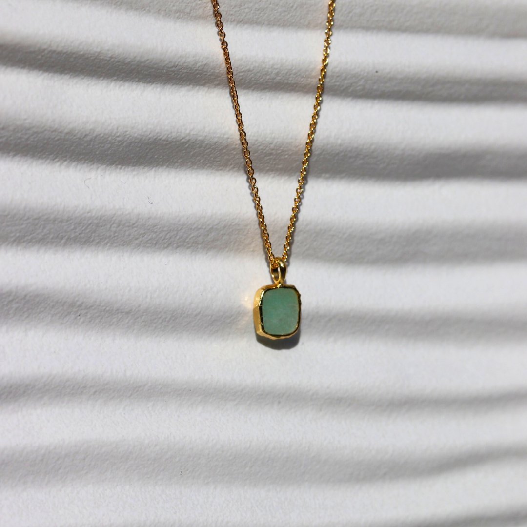 Photo of green stone gold plated necklace on a white background.