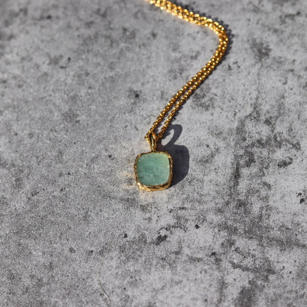 Photo of green stone gold plated necklace on a grey marble effect background