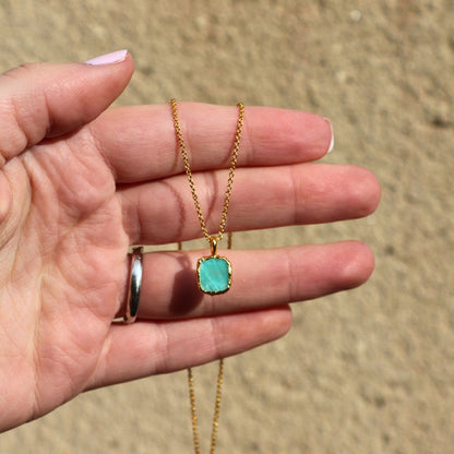 Photo of amazonite blue stone gold plated necklace held in a females hand.