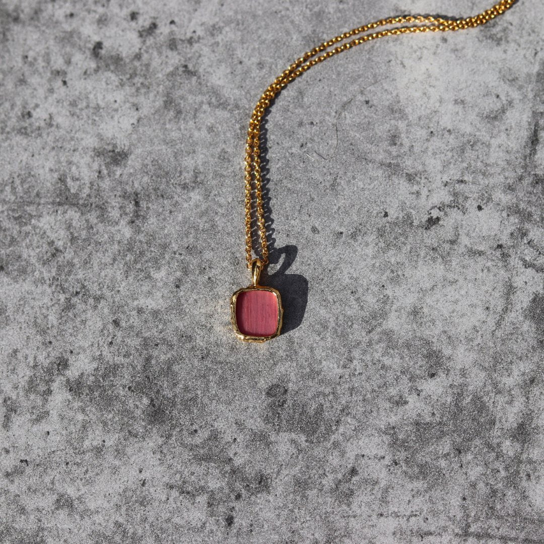 Photo of red stone gold plated necklace on a grey marble effect background.