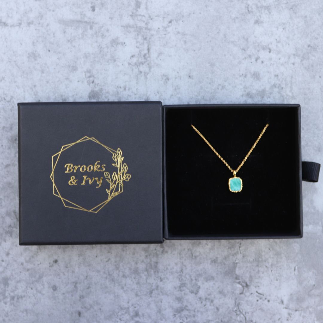 Photo of amazonite blue stone gold plated necklace inside gift box on a grey marble effect background.