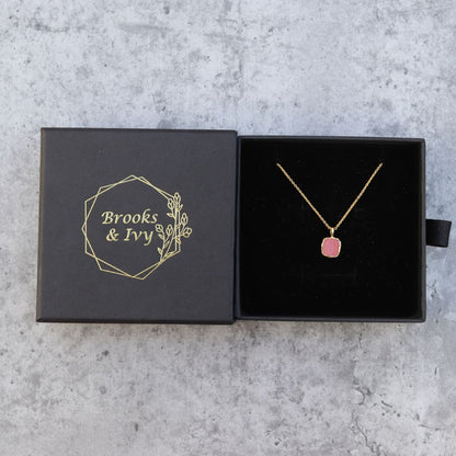 Photo of red stone gold plated necklace inside gift box on a grey marble effect background.