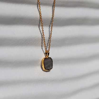 Photo of grey stone gold plated necklace on a white background.