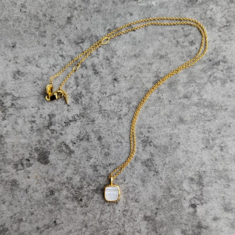 Photo of white stone gold plated necklace on a grey marble effect background.